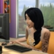 The Sims 4 - A sim plays on a computer with a smile