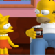 3D videogame versions of Homer and Lisa Simpson sit on the couch in a screenshot from The Simpsons: Hit & Run.