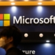 An image of a man in a protective facemask walking past a Microsoft logo.