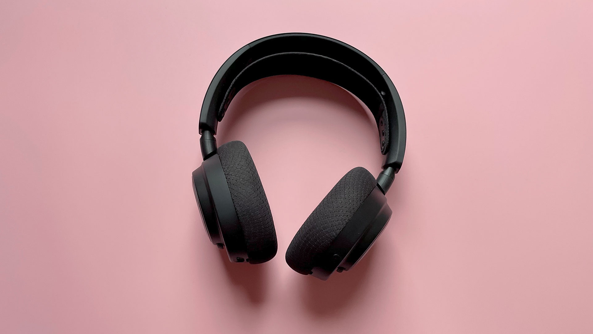 The SteelSeries Arctis Nova 7 Wireless on a pink background.