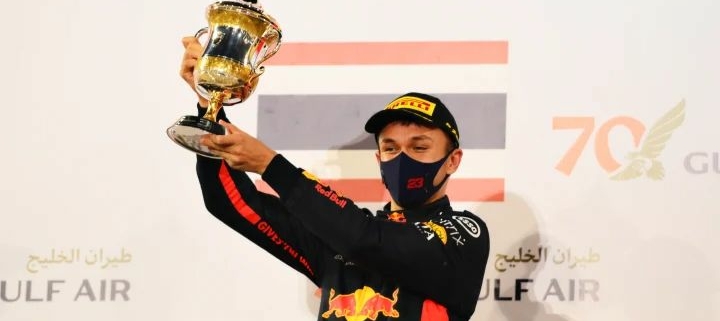 Alex Albon holding a podium trophy.