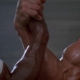 Two glistening, muscular arms shaking hands/arm wrestling in the air sourced from the film Predator