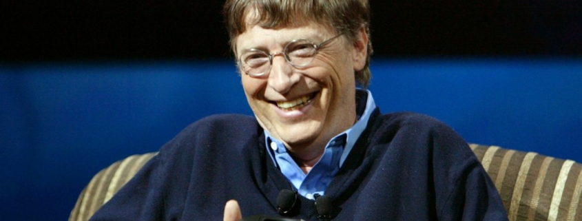 Bill Gates in 2005 holding an Xbox controller and smiling.