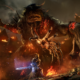 The Spurned Progeny from Lords of the Fallen looms horrifically over a player amidst burning rubble, a clawed hand tearing from its maw to snatch them up.