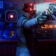 Cyborg man holding a laser pistol in front of monitor that says