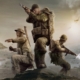 Company of Heroes 3 key art - three Allied soldiers on a rocky peak, shooting and throwing grenades at enemies