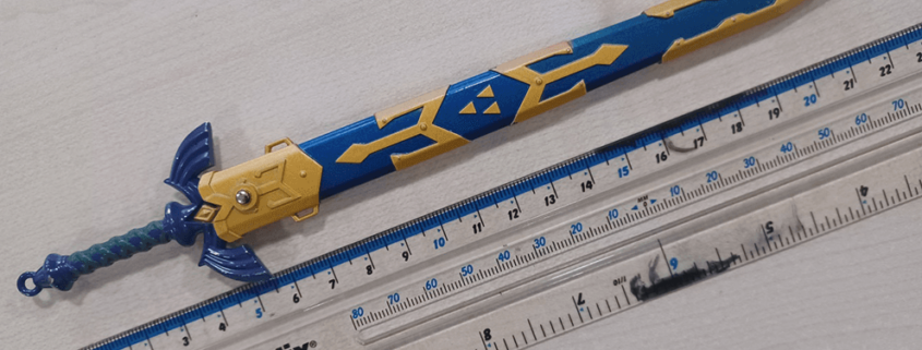 A small Master Sword replica compared against a ruler, measuring 6 inches.