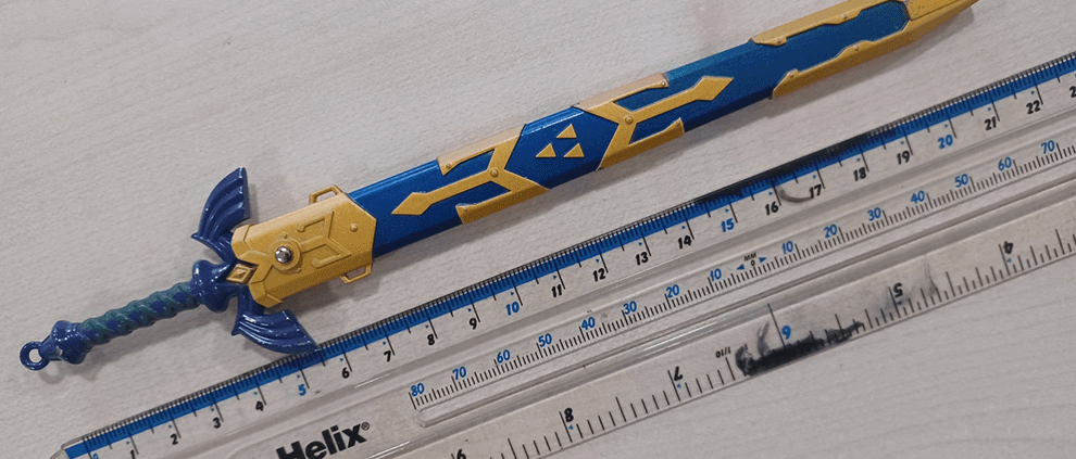 A small Master Sword replica compared against a ruler, measuring 6 inches.