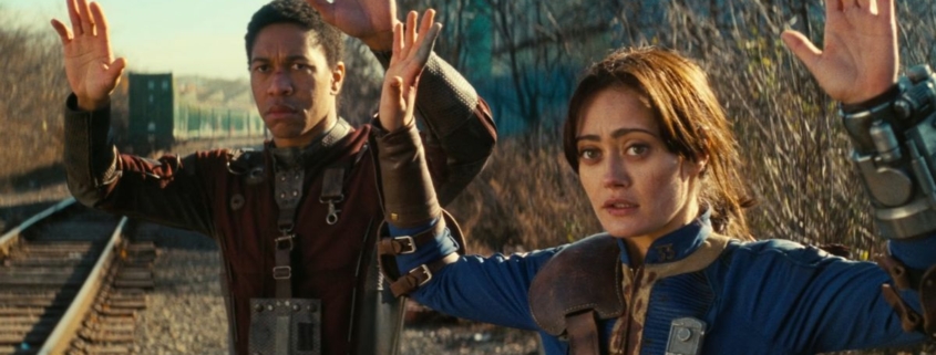 Lucy and Max from Fallout with their hands up