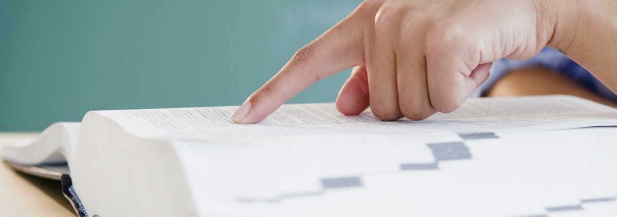 A hand pointing at an entry in an open dictionary.