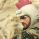 Punished &quot;Venom&quot; Snake looking menacingly over his shoulder to the left while wearing a silly chicken hood.