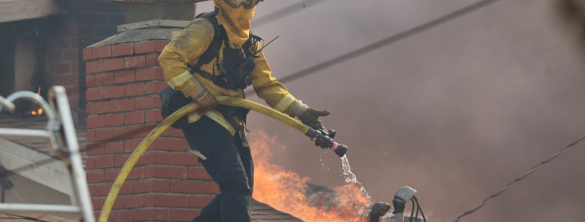 A cropped Cal Fire photo of a firefighter on a rooftop during the 2025 Palisades Fire.