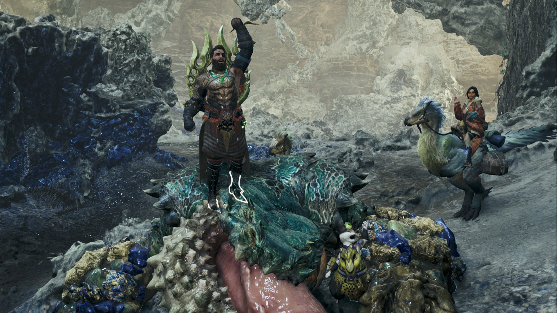 A hunter cheers atop the corpse of a slain Chatacabra in Monster Hunter Wilds. Their palico mimics their posture nearby, while Alma waves from atop her Seikret in the background.